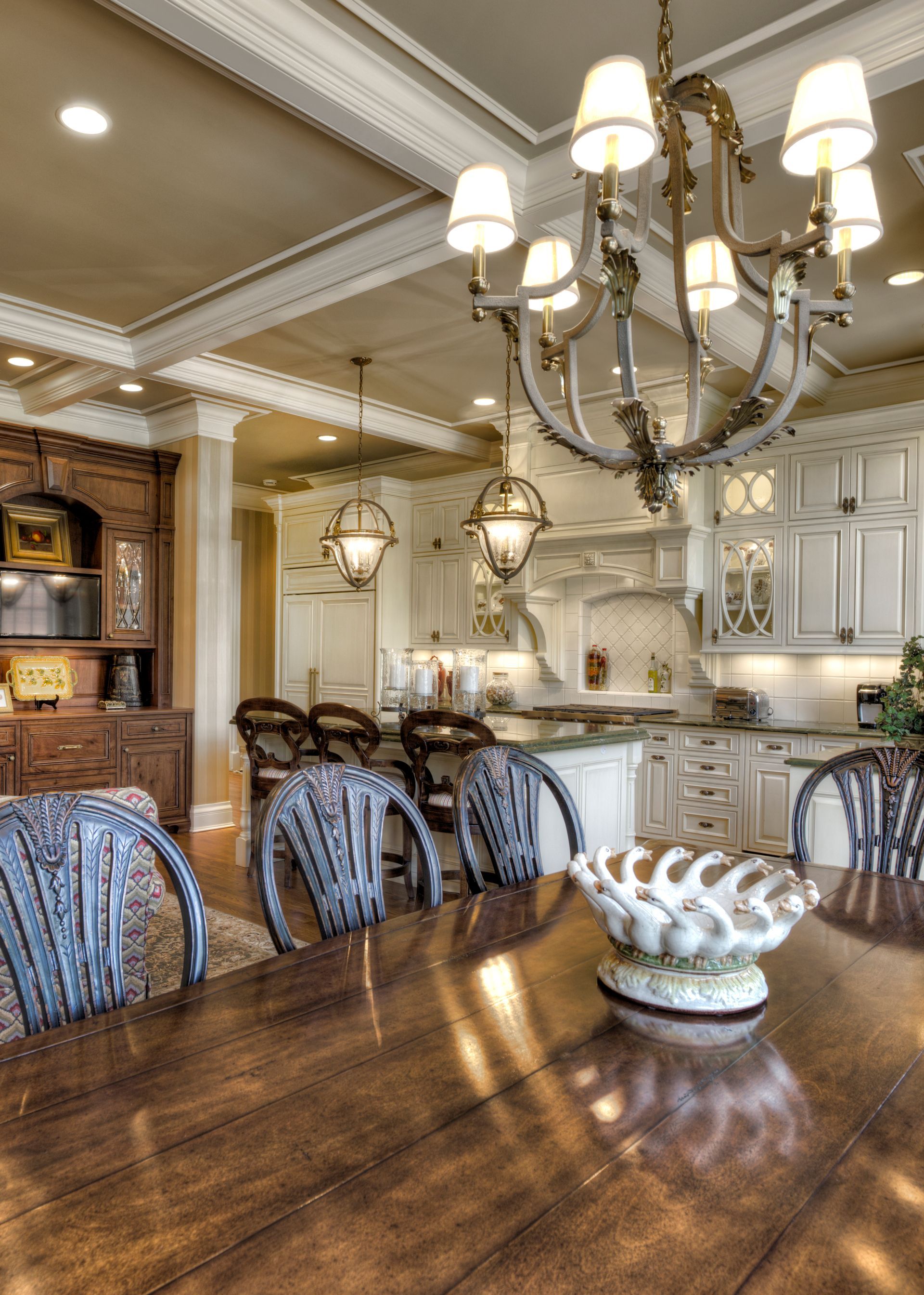 A dining room table with chairs and a chandelier hanging from the ceiling.