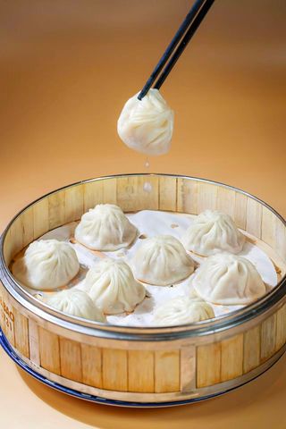 Plate of golden fried dumplings on a white dish, with chopsticks lifting one above it.