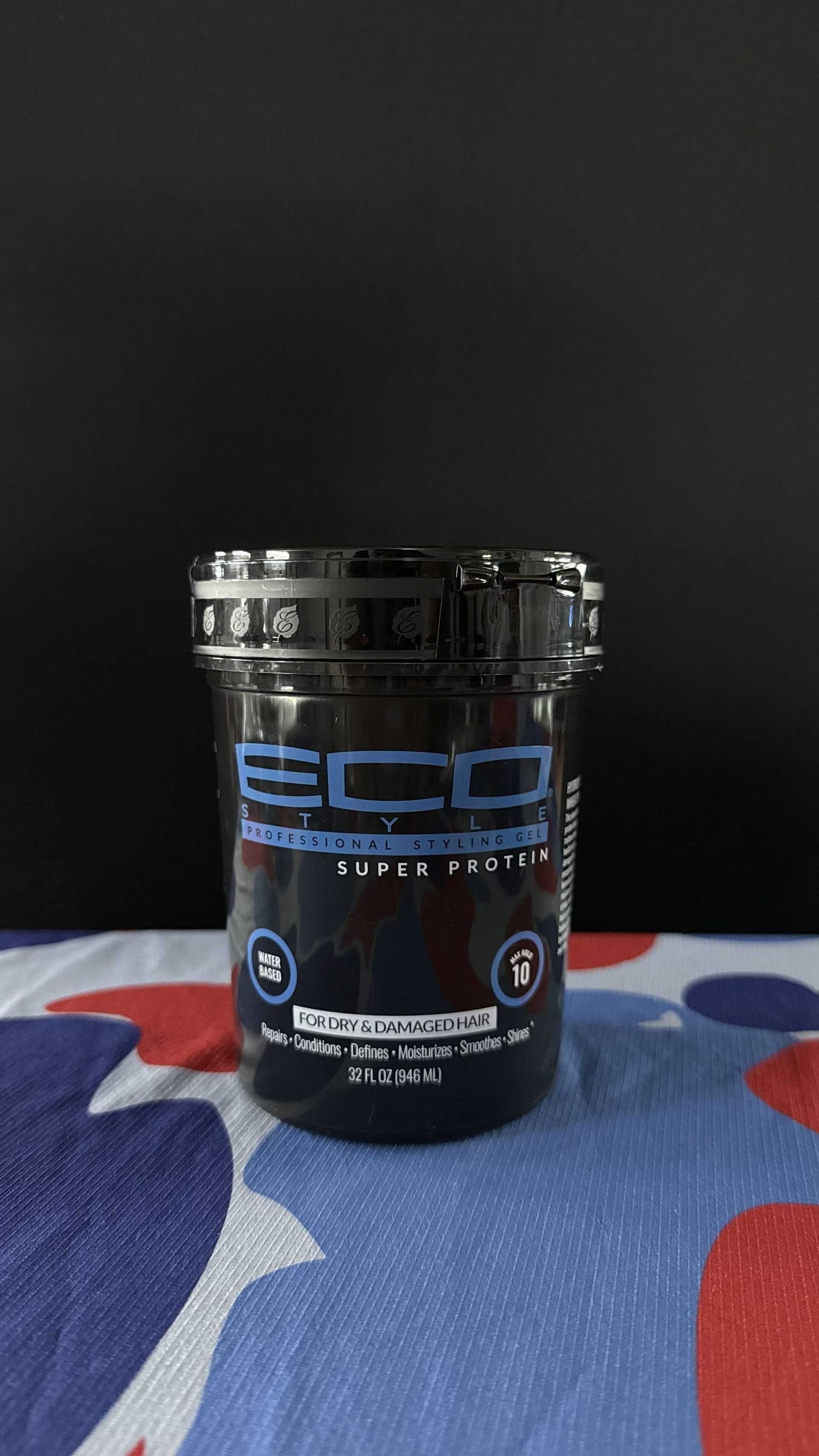 A black container of ECD Super Protein powder sits on a patterned cloth surface against a solid black background.