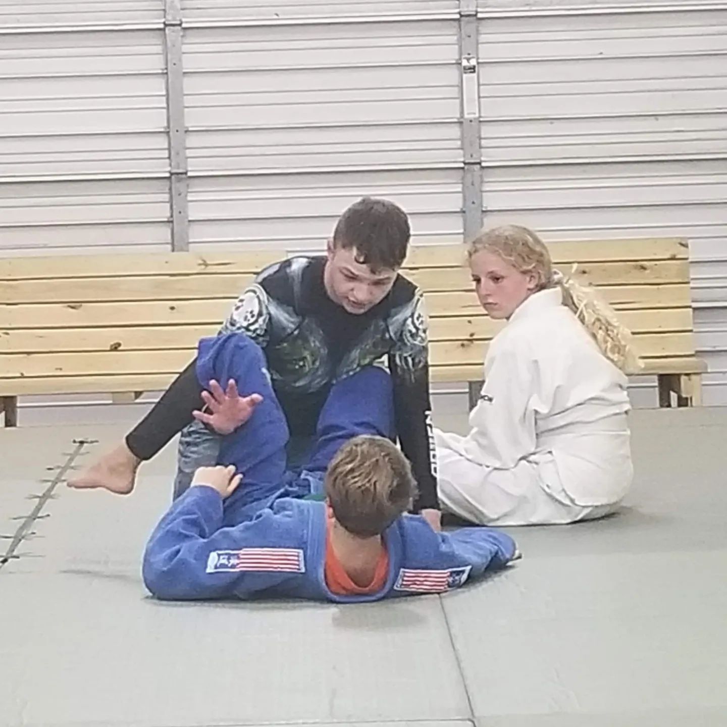 A man and a woman are practicing jiu jitsu on a mat.
