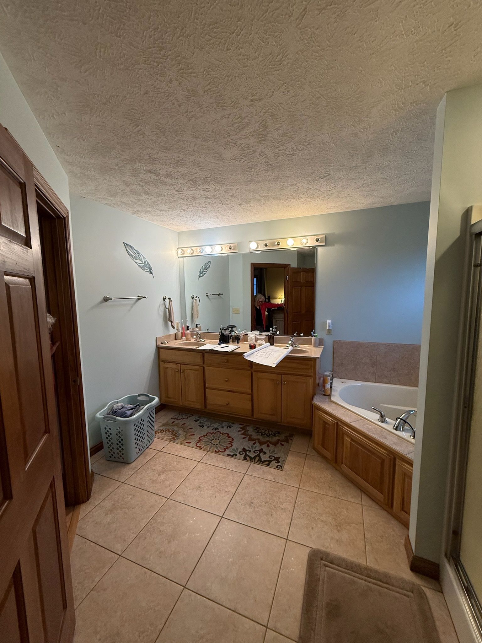 Bathroom with double vanity, tan tile floor, blue walls, and corner tub.