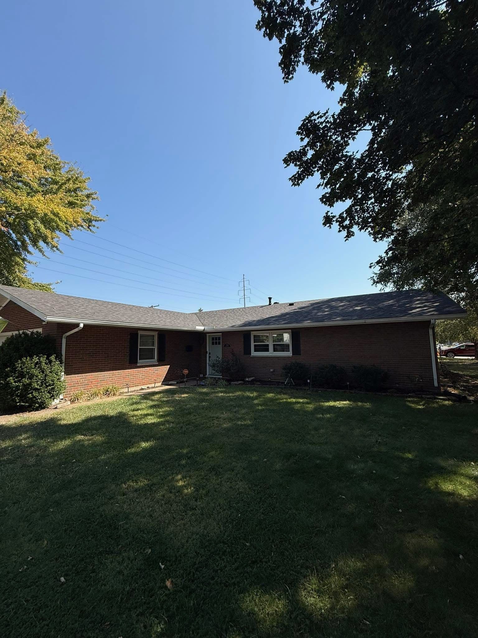 Brick house with brown garage door, small garden, and blue sky over a driveway