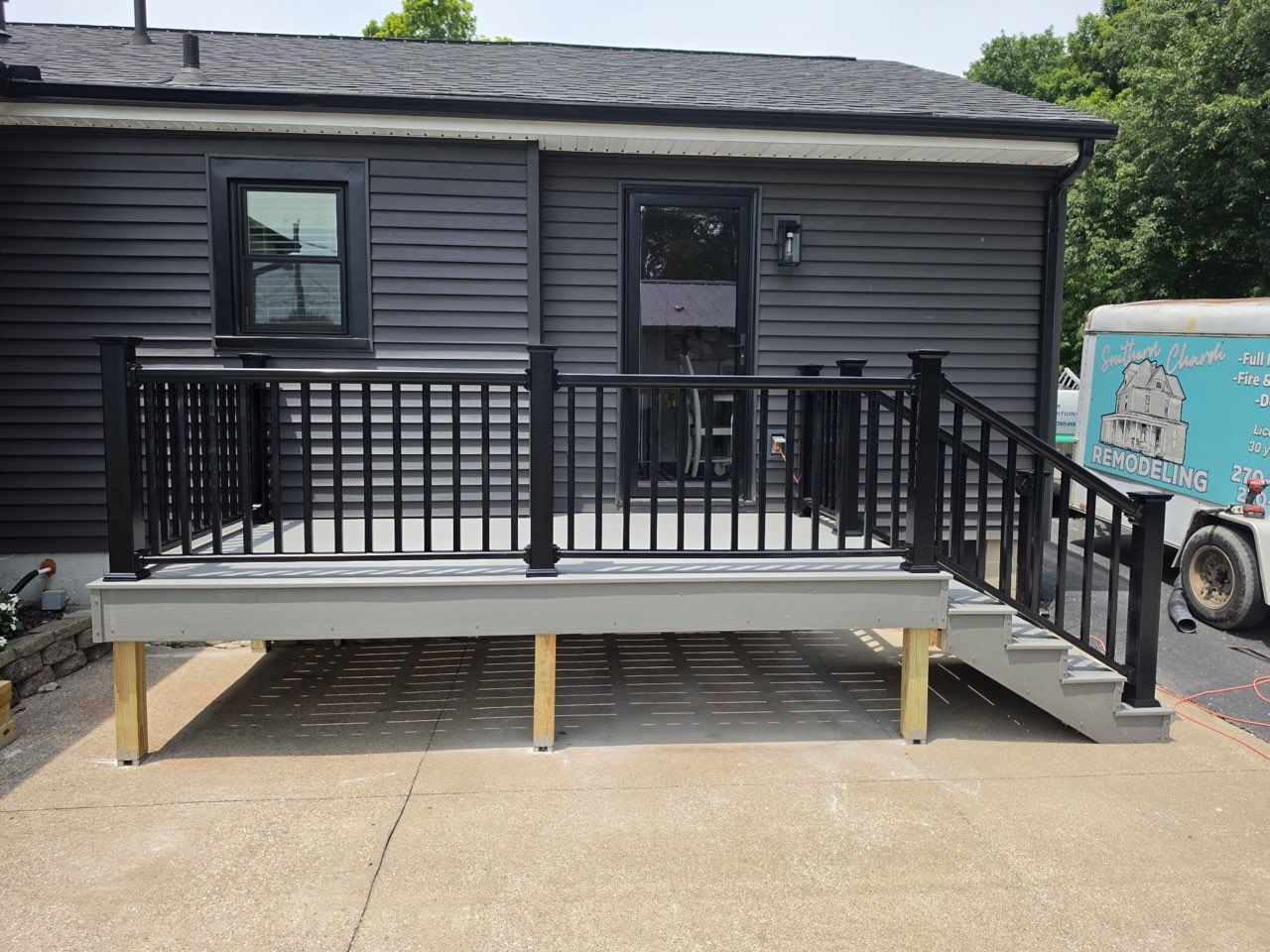 Accessible ramp and deck with black railings attached to a dark gray building