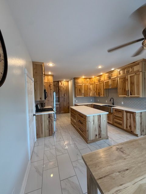 Bright kitchen with wood cabinets, white tile floor, island, and stainless appliances