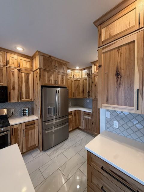 Wooden kitchen with stainless steel fridge, light tile floor, and white countertops