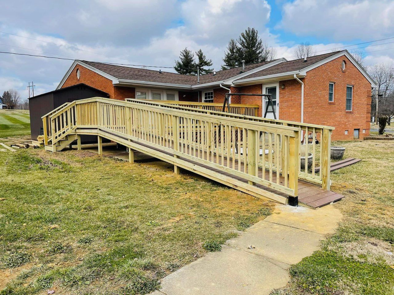 Brick building with a long wooden wheelchair ramp and handrails leading to the entrance.