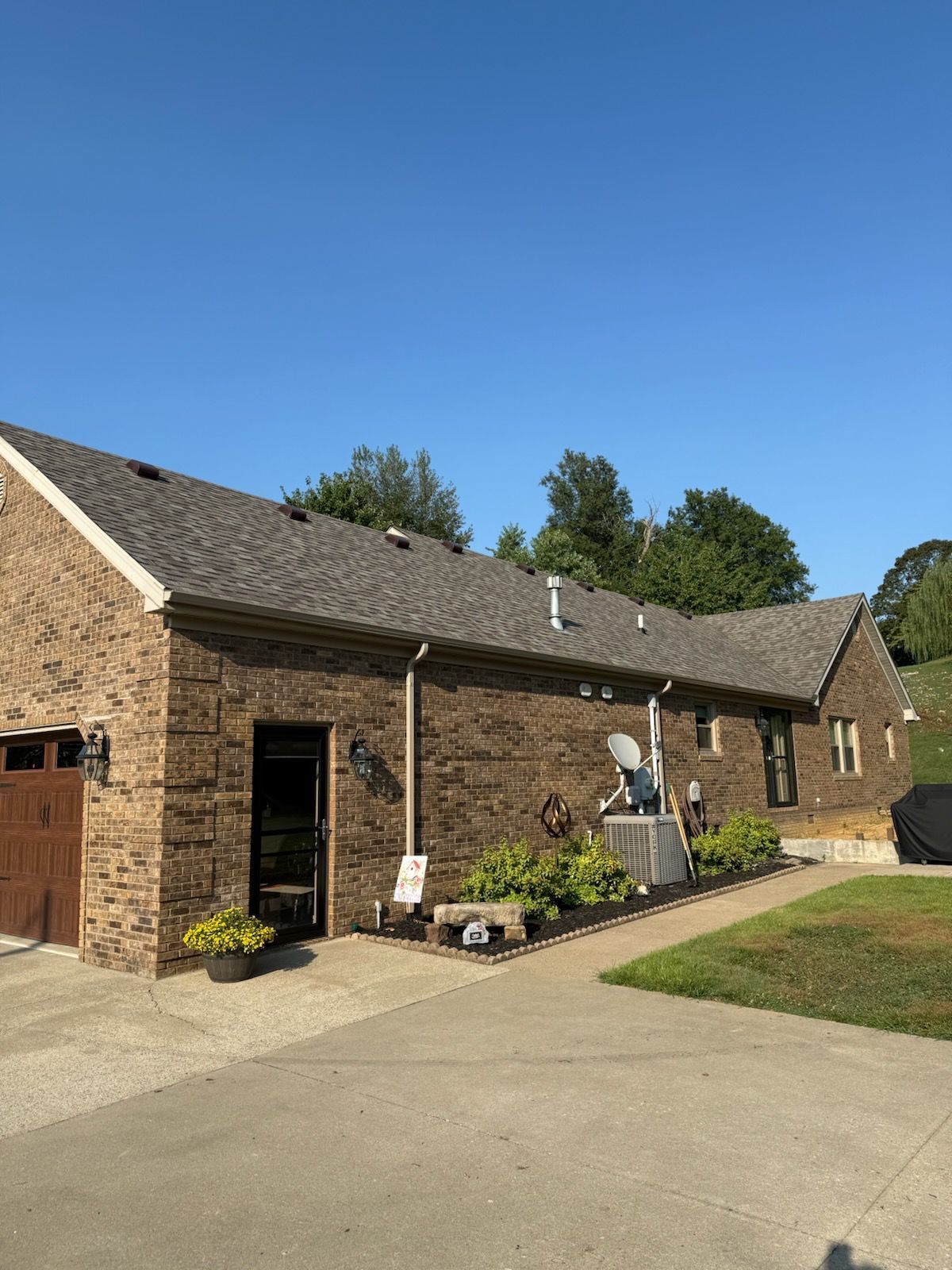 Brick house with garage, driveway, and front garden under a clear blue sky