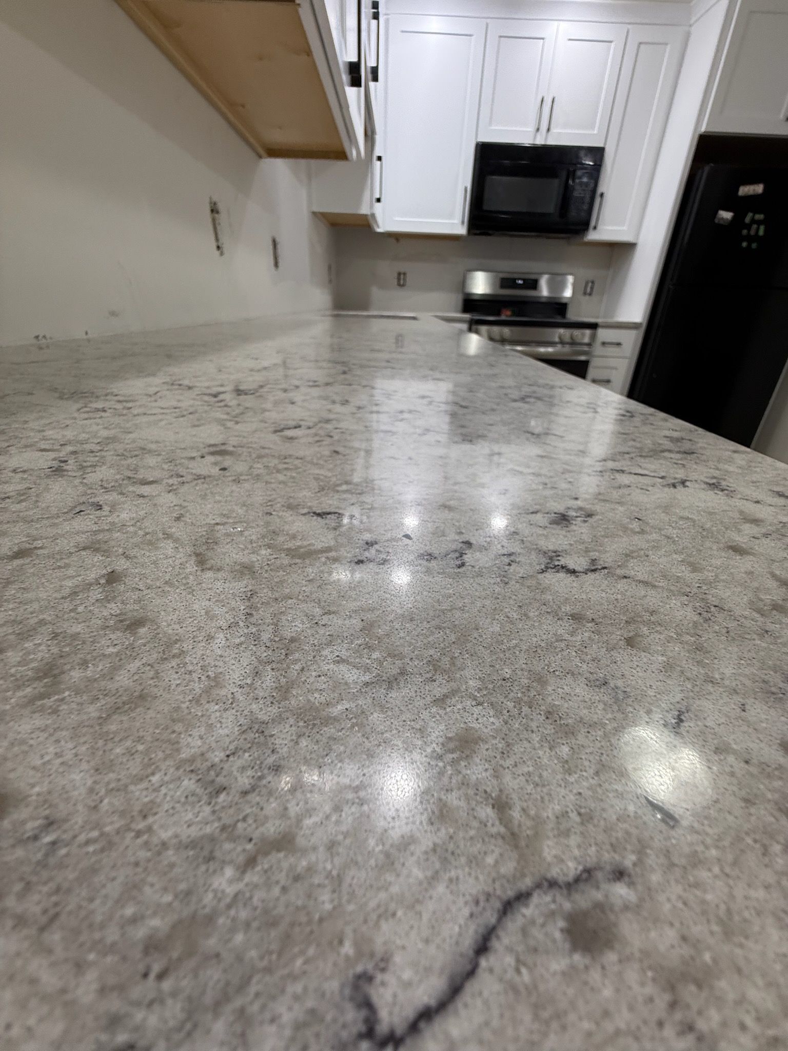 Granite kitchen countertop with speckled gray-white surface and built-in microwave in the background
