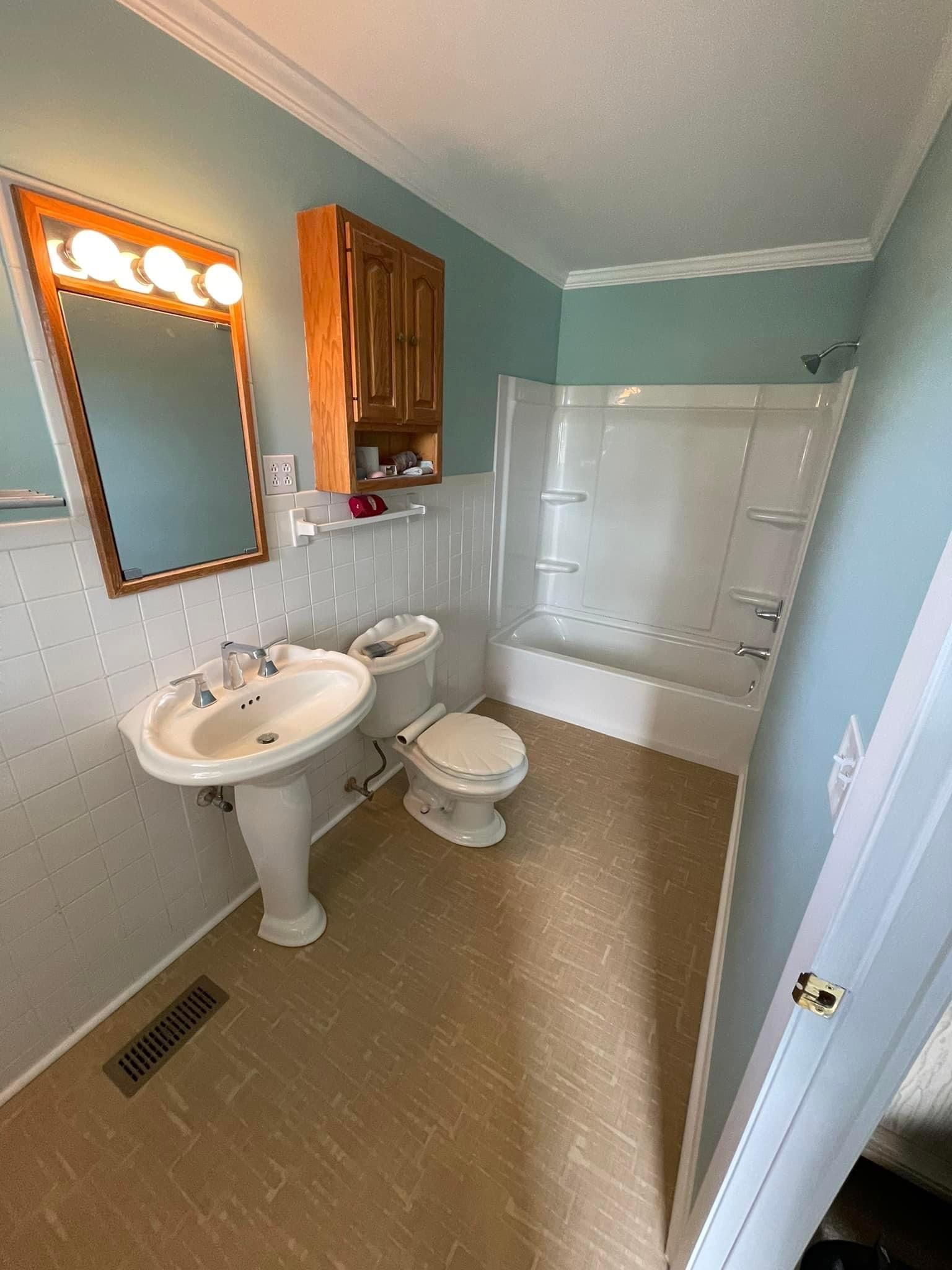 Bathroom with pedestal sink, mirror, toilet, and shower in light blue and white tones