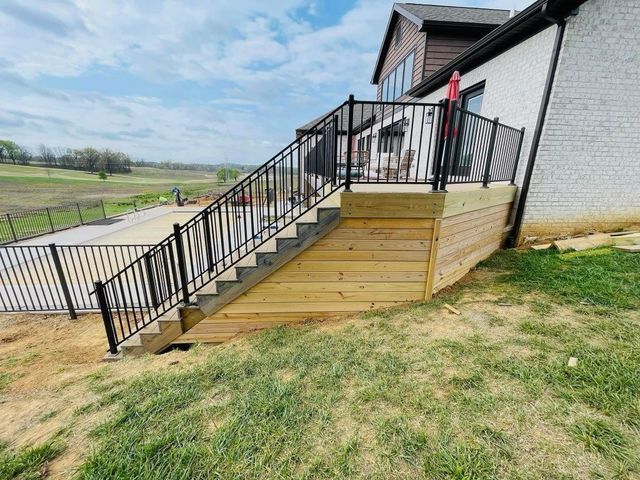 Outdoor wooden ramp and stairs with black railings leading to a house