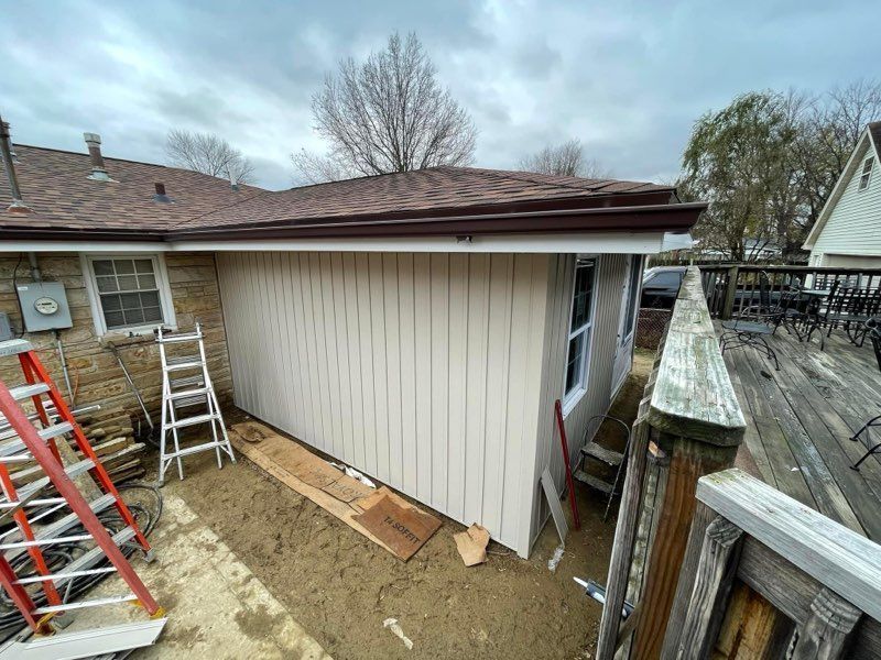 Backyard shed under construction with ladders, wood planks, and a leaning fence beside it