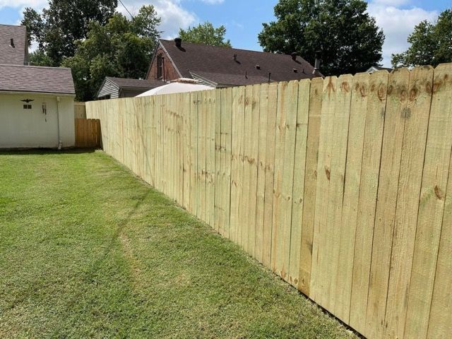 New wooden privacy fence along a grassy backyard beside neighboring houses