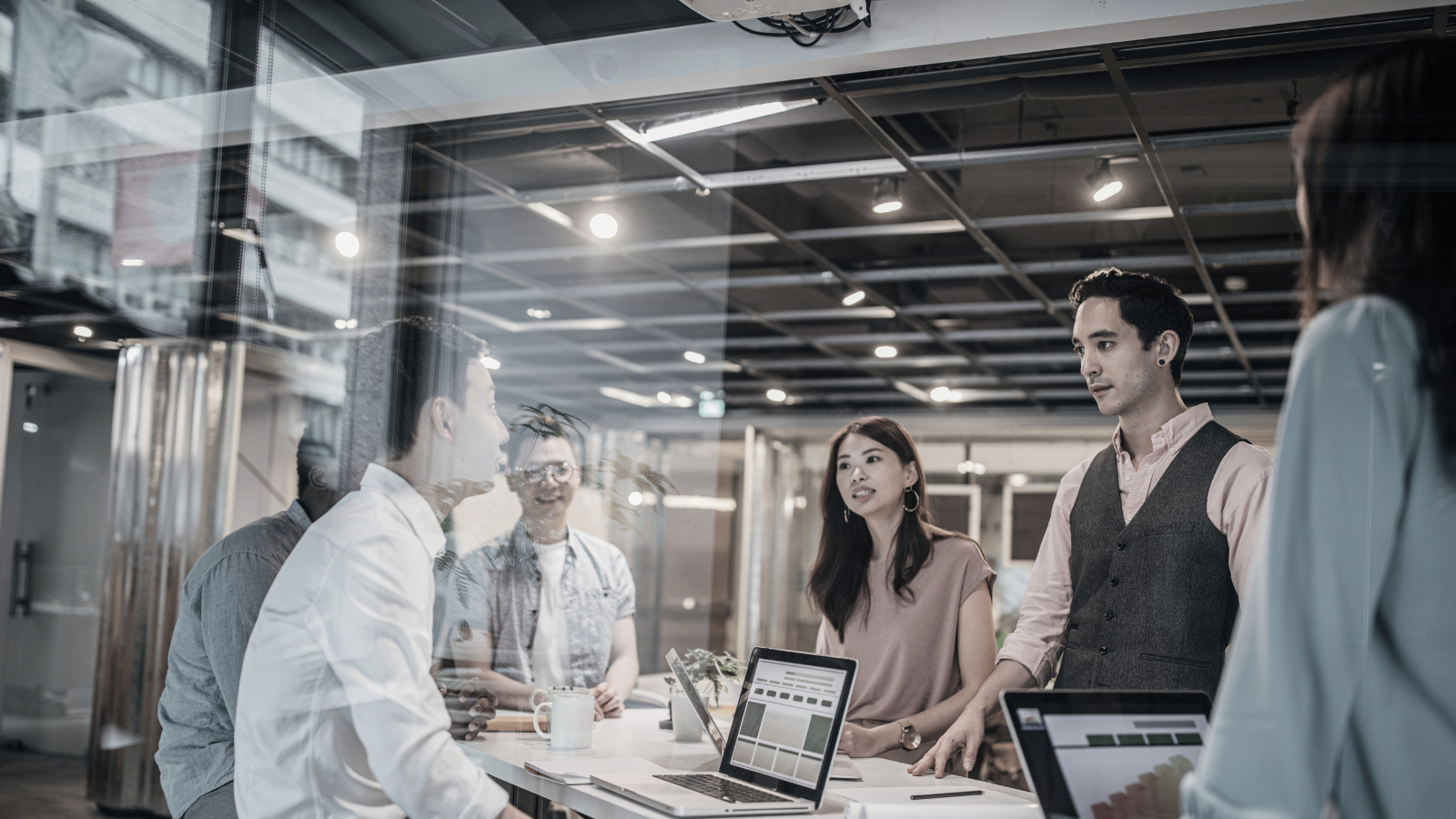 Business team in a meeting around a laptop, reviewing documents in a bright office