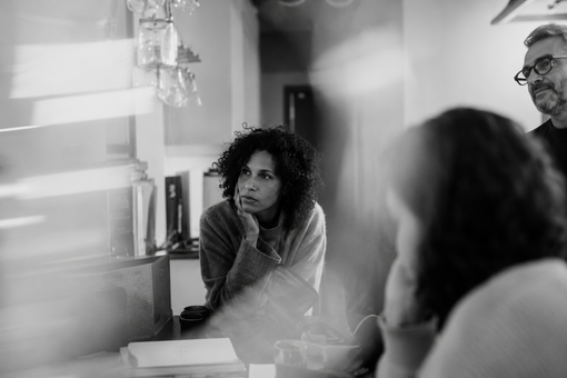 People in a meeting room, one person listening intently across a table