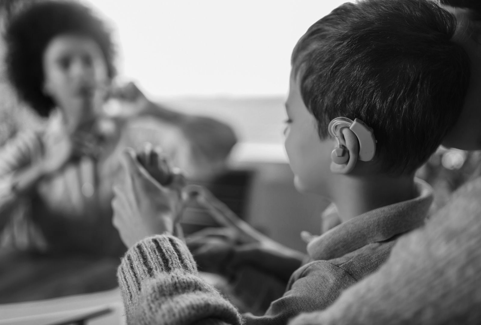 Boy listening to a speaker, seen in profile, in a classroom setting