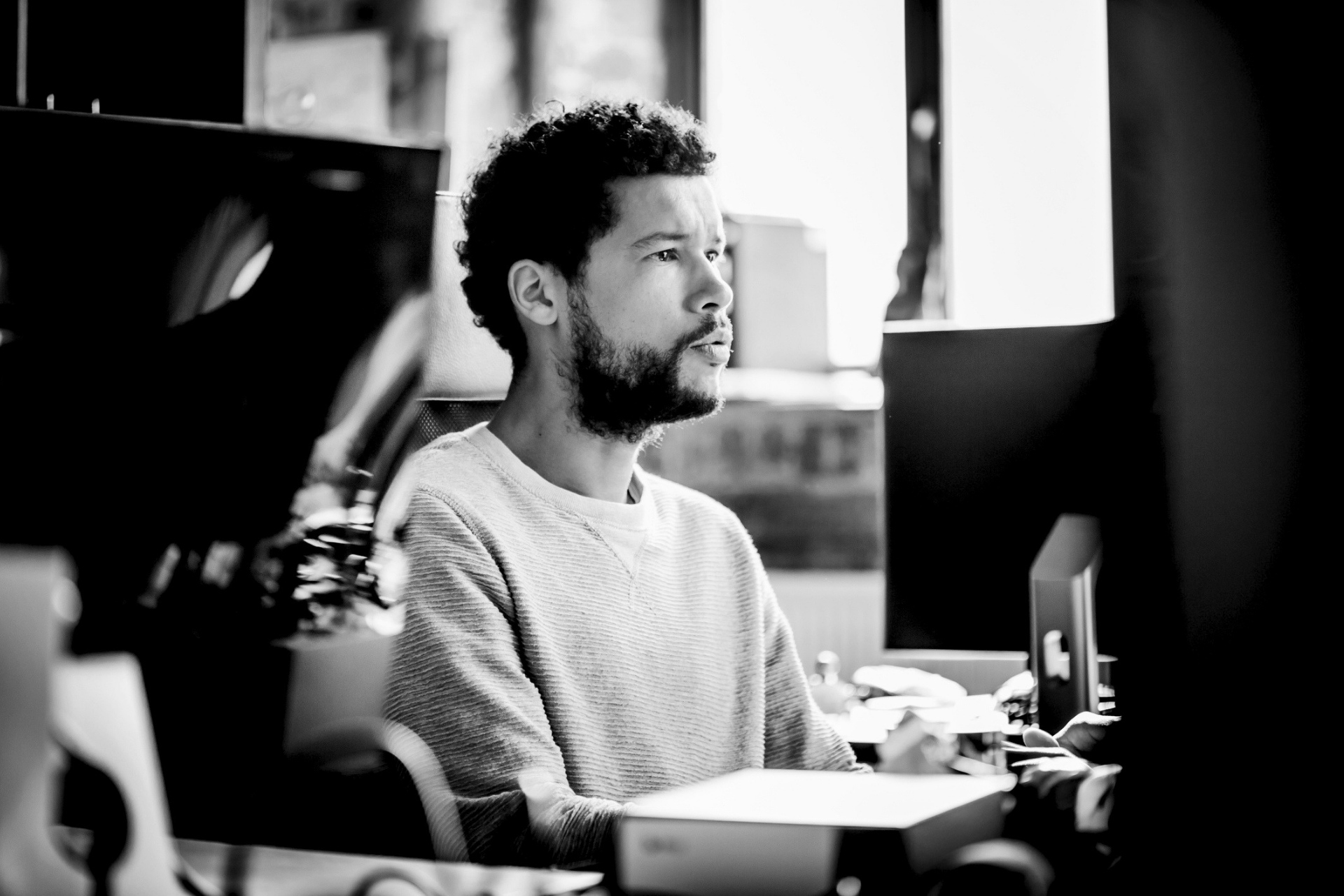 Person working at a desk in a bright office, looking at a computer screen