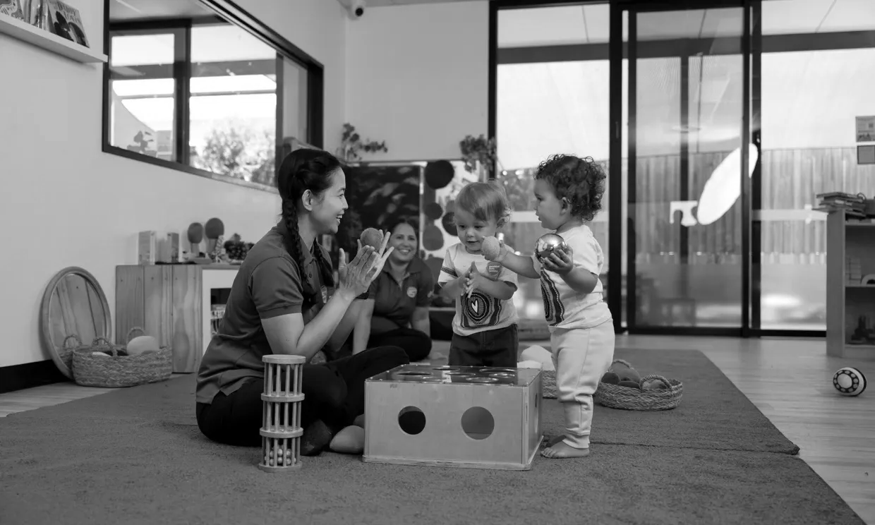 Three children playing with blocks on a rug in a bright room