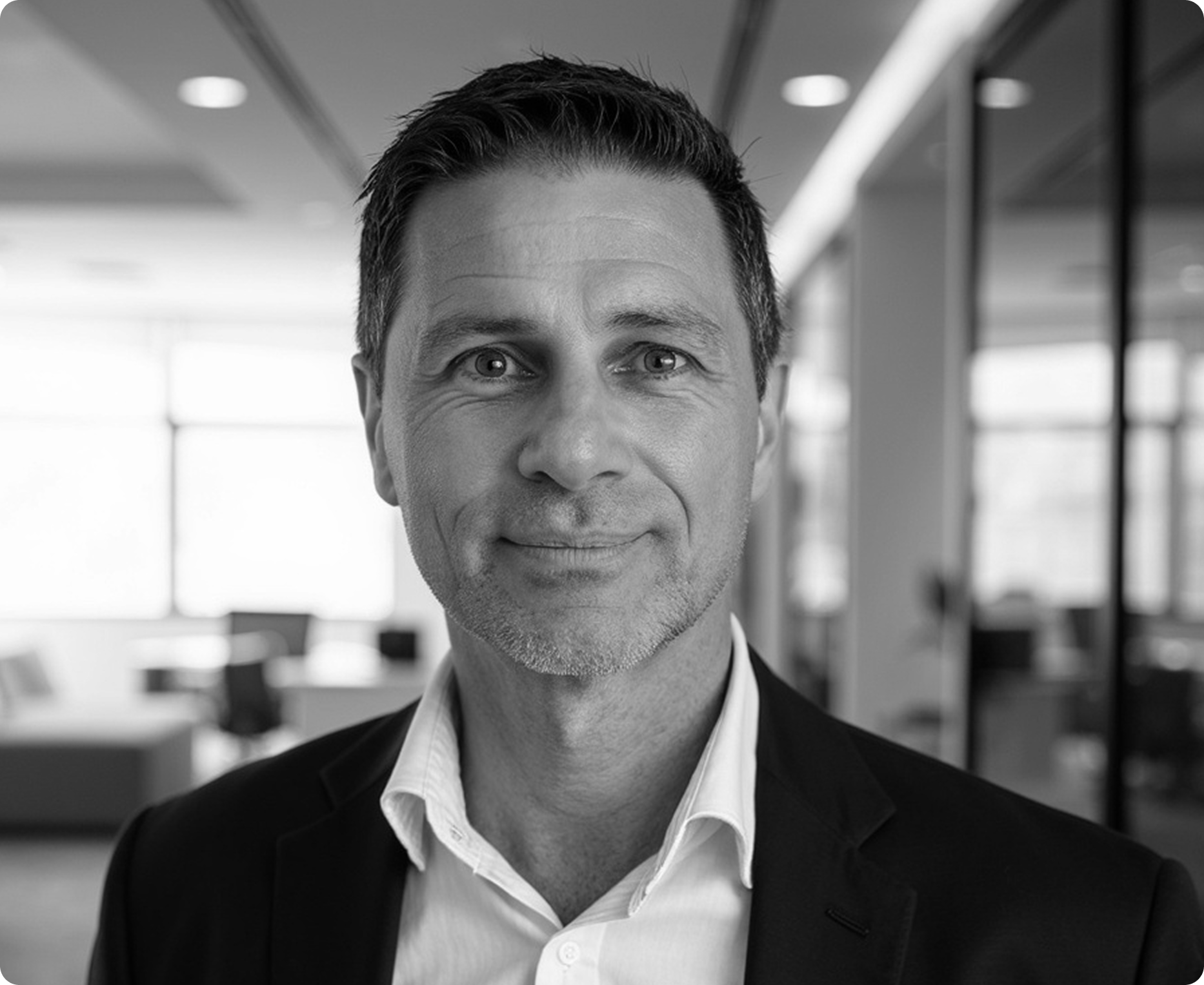Portrait of a man in a dark blazer and white shirt in a modern office setting