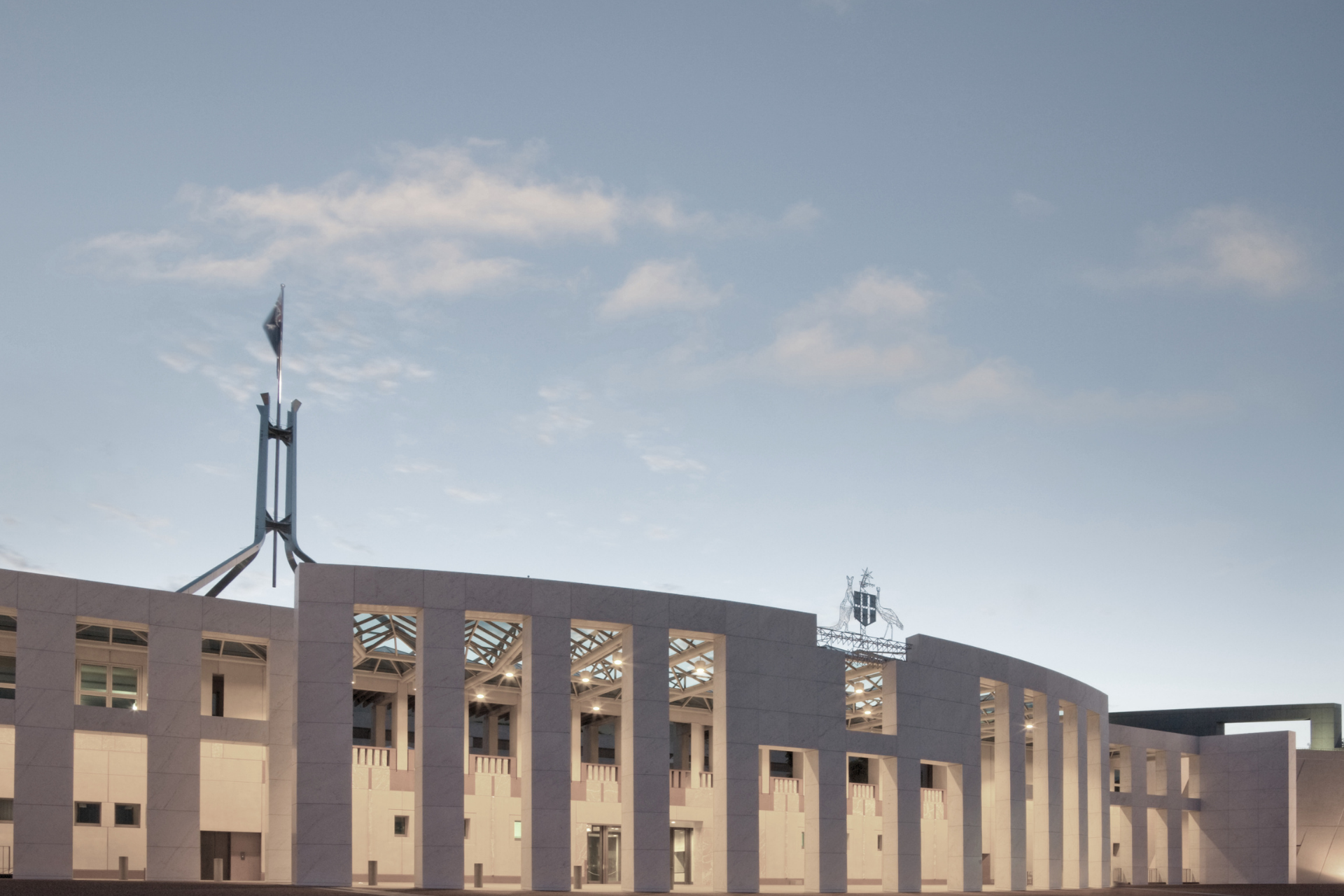 Wide view of a modern government building with tall columns against a partly cloudy sky