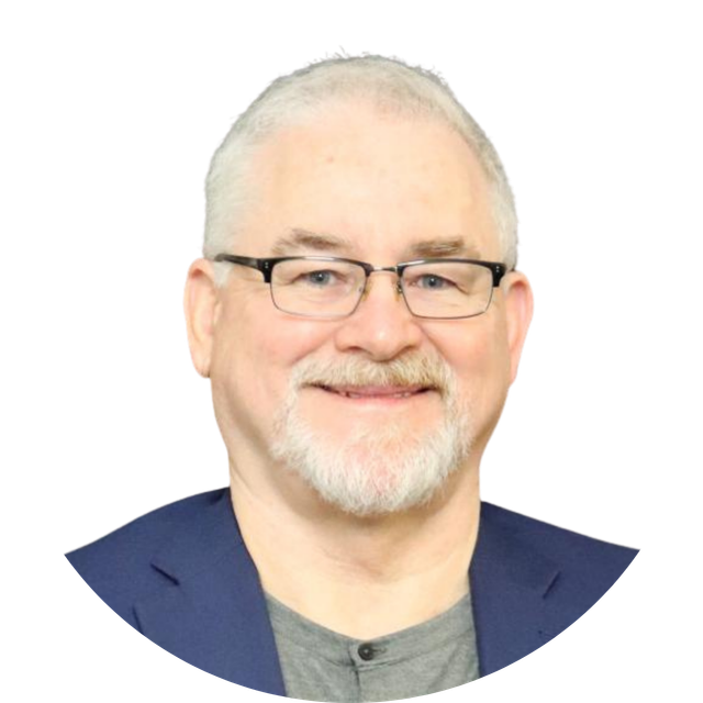 Portrait of a smiling man with glasses, gray hair, and a navy blazer on a white background