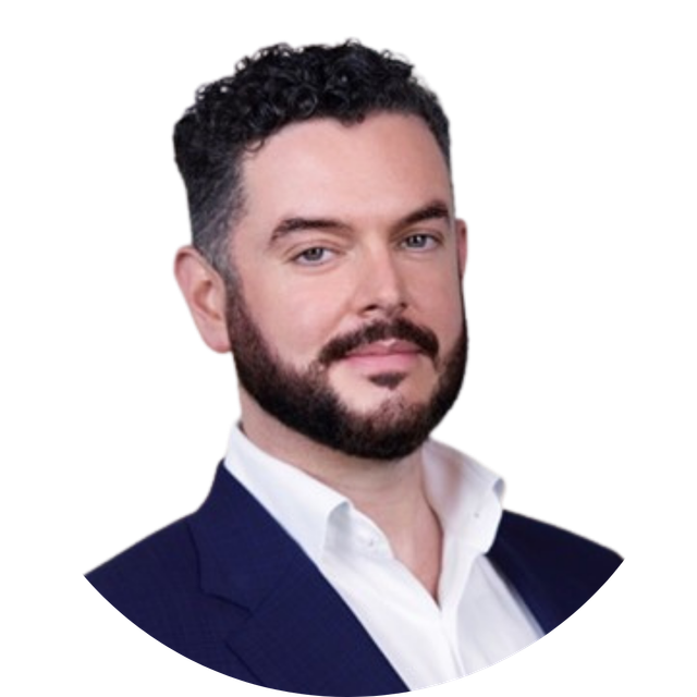 Studio headshot of a man in a navy blazer and white shirt on a white background