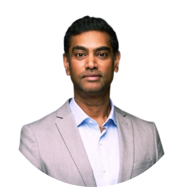 Studio portrait of a man in a light gray blazer and blue shirt against a white background