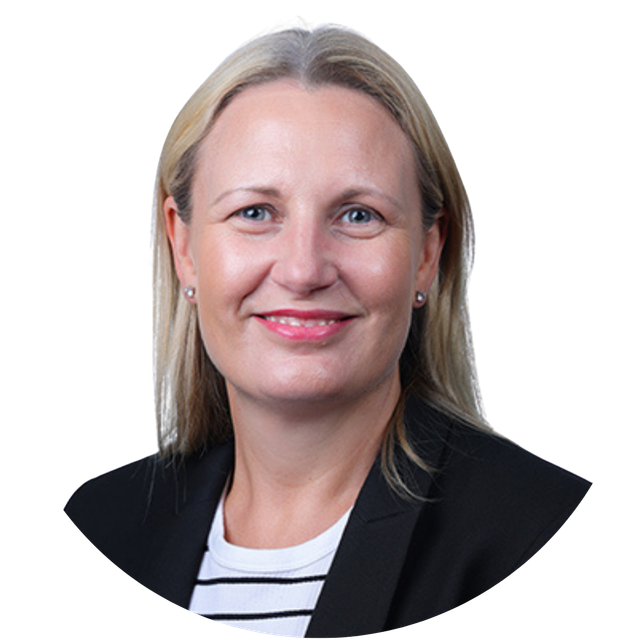 Studio headshot of a smiling woman in a black blazer and striped top on a white background