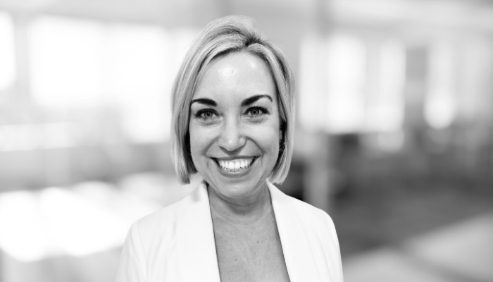 Smiling business professional, posing indoors in black and white.