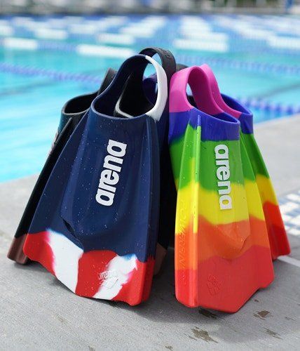 A pair of colorful swim fins are sitting on the edge of a pool.