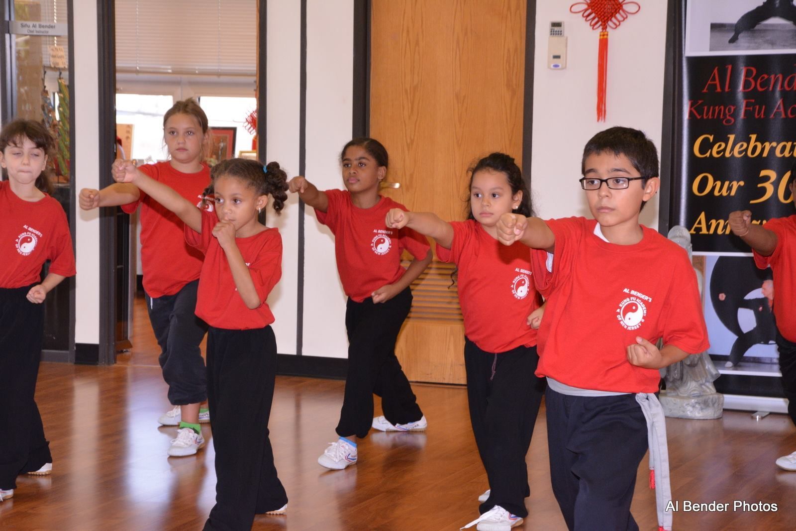 A group of children wearing red shirts are practicing martial arts