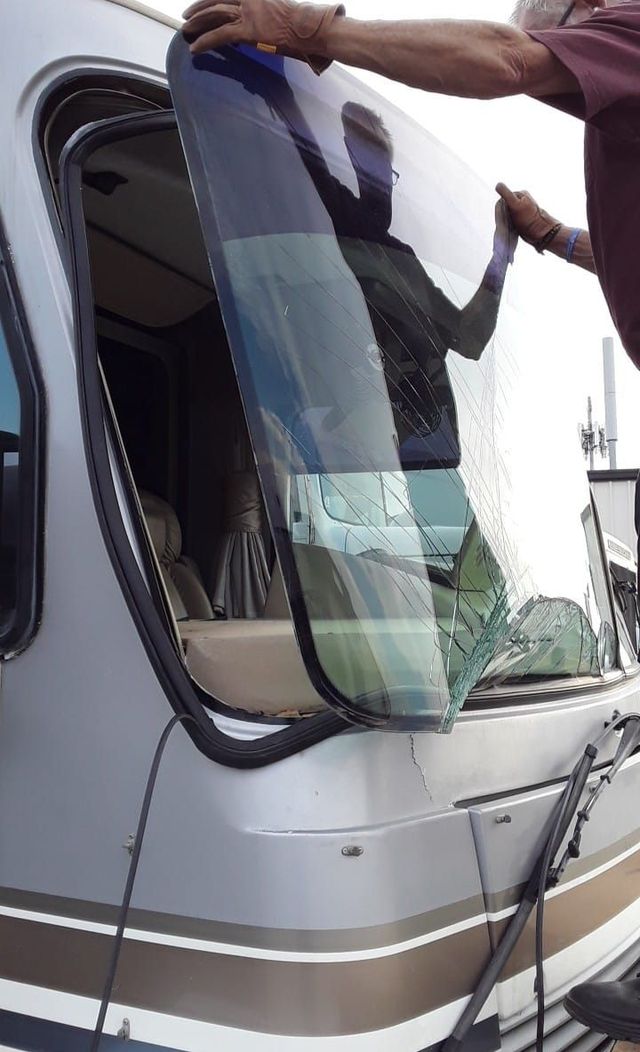 Person installing a tinted window panel on a silver RV