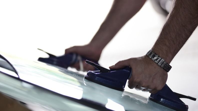 Hands gripping a dark blue mop or squeegee on a wet floor.