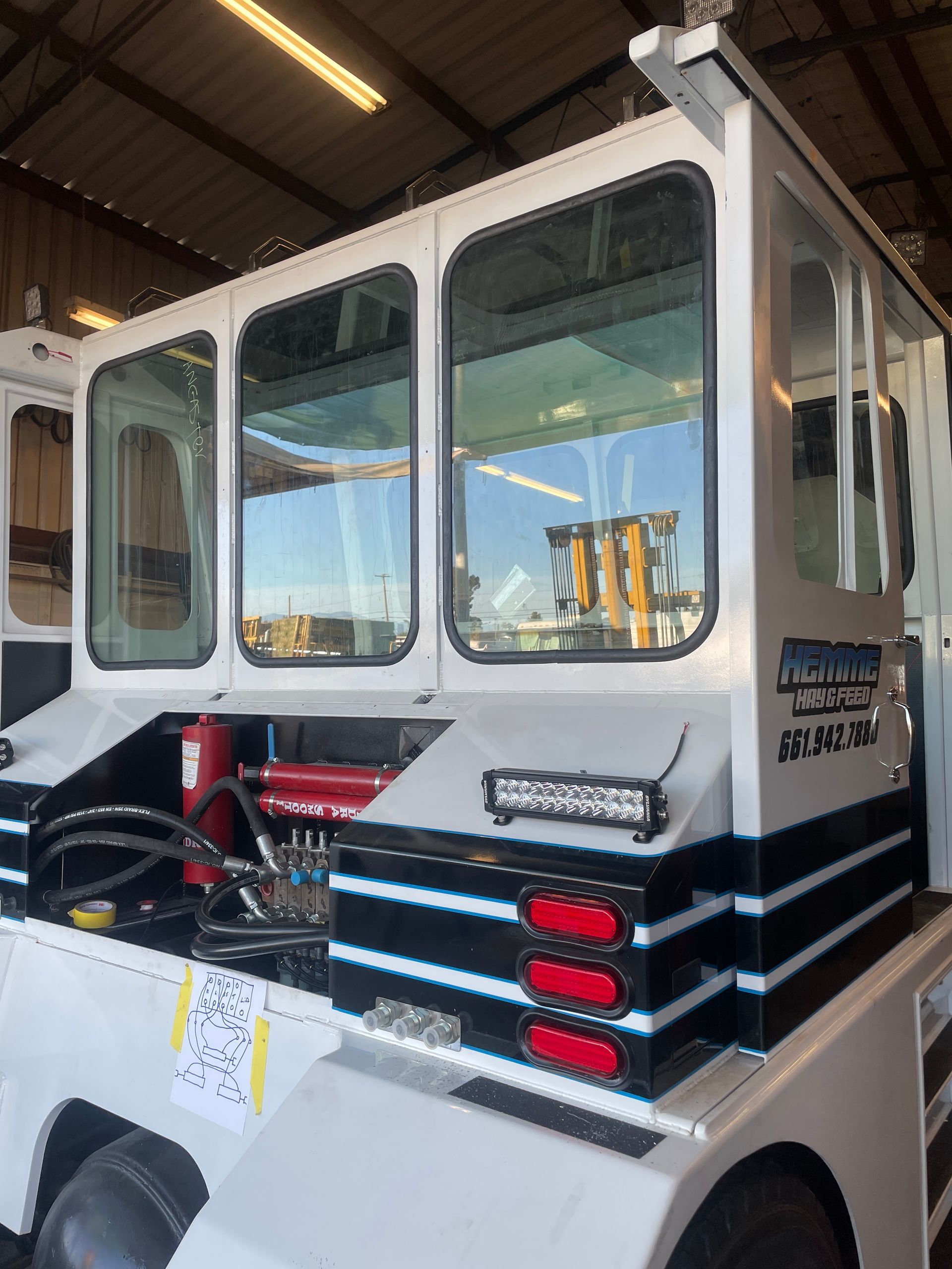 White boat cabin with large windows and red-black safety equipment in an indoor workshop