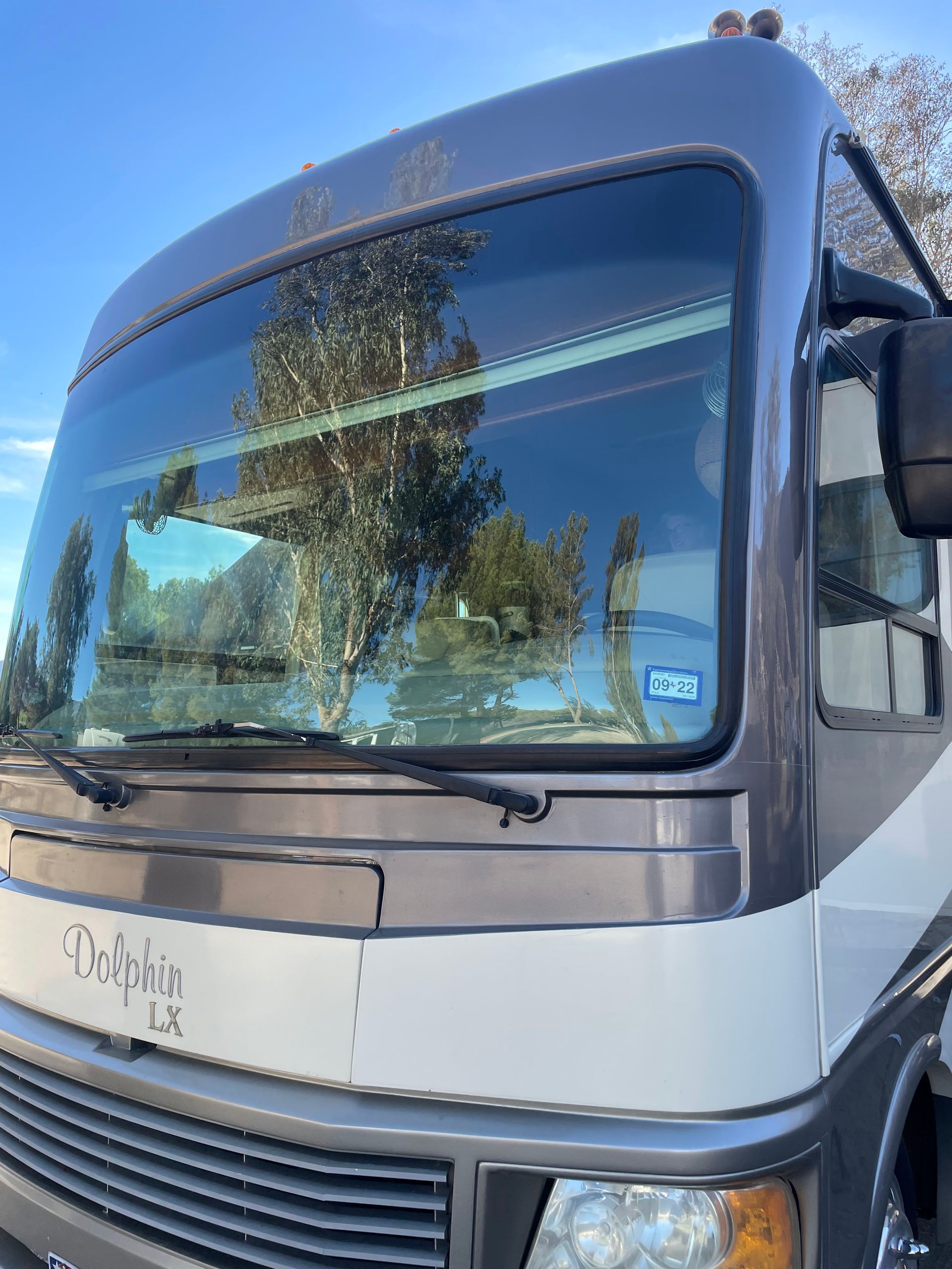 Front view of a silver and black bus with large windshield under a clear blue sky