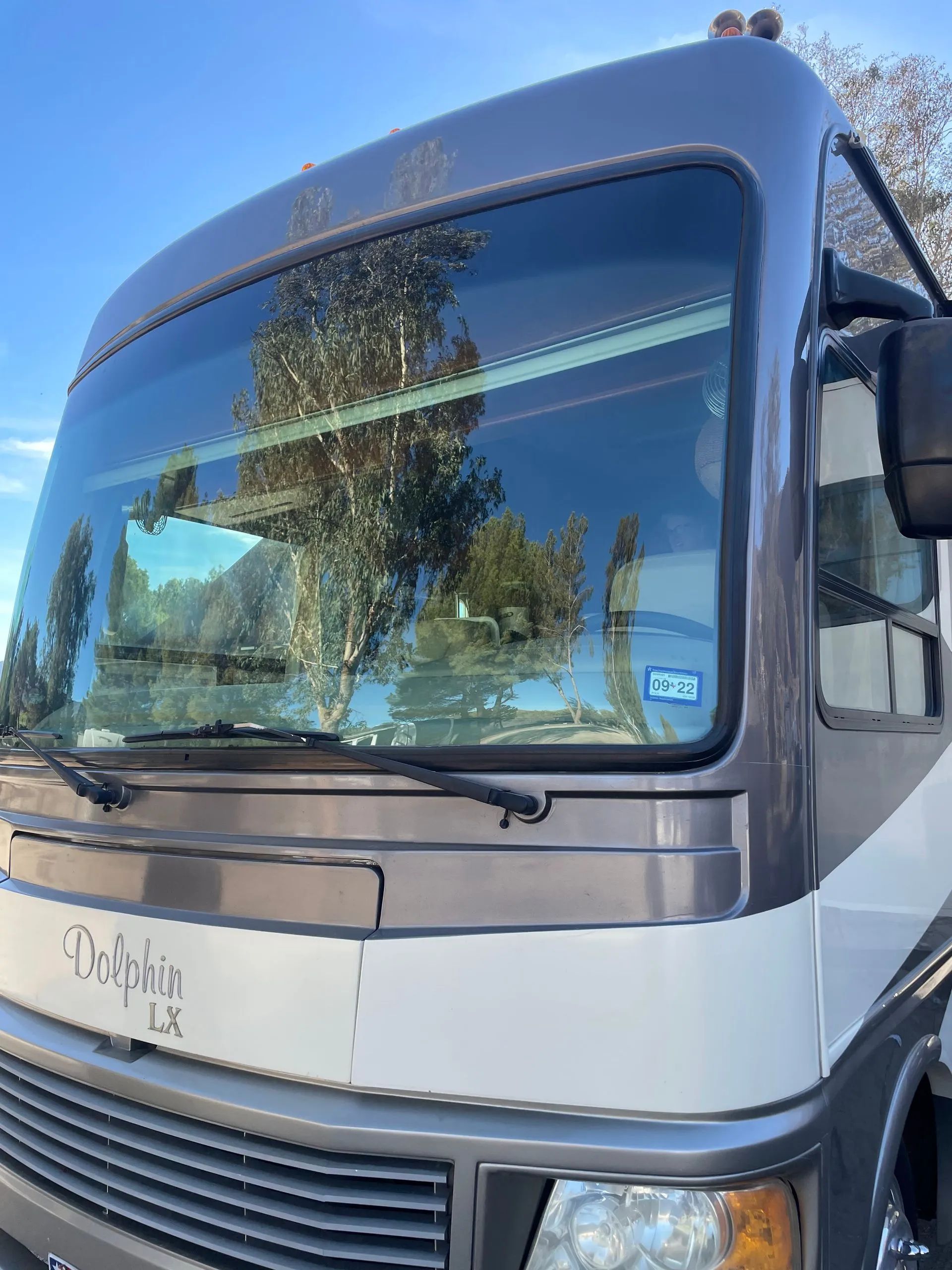 Front view of a gray and black motorhome with large windshield and side mirror outdoors