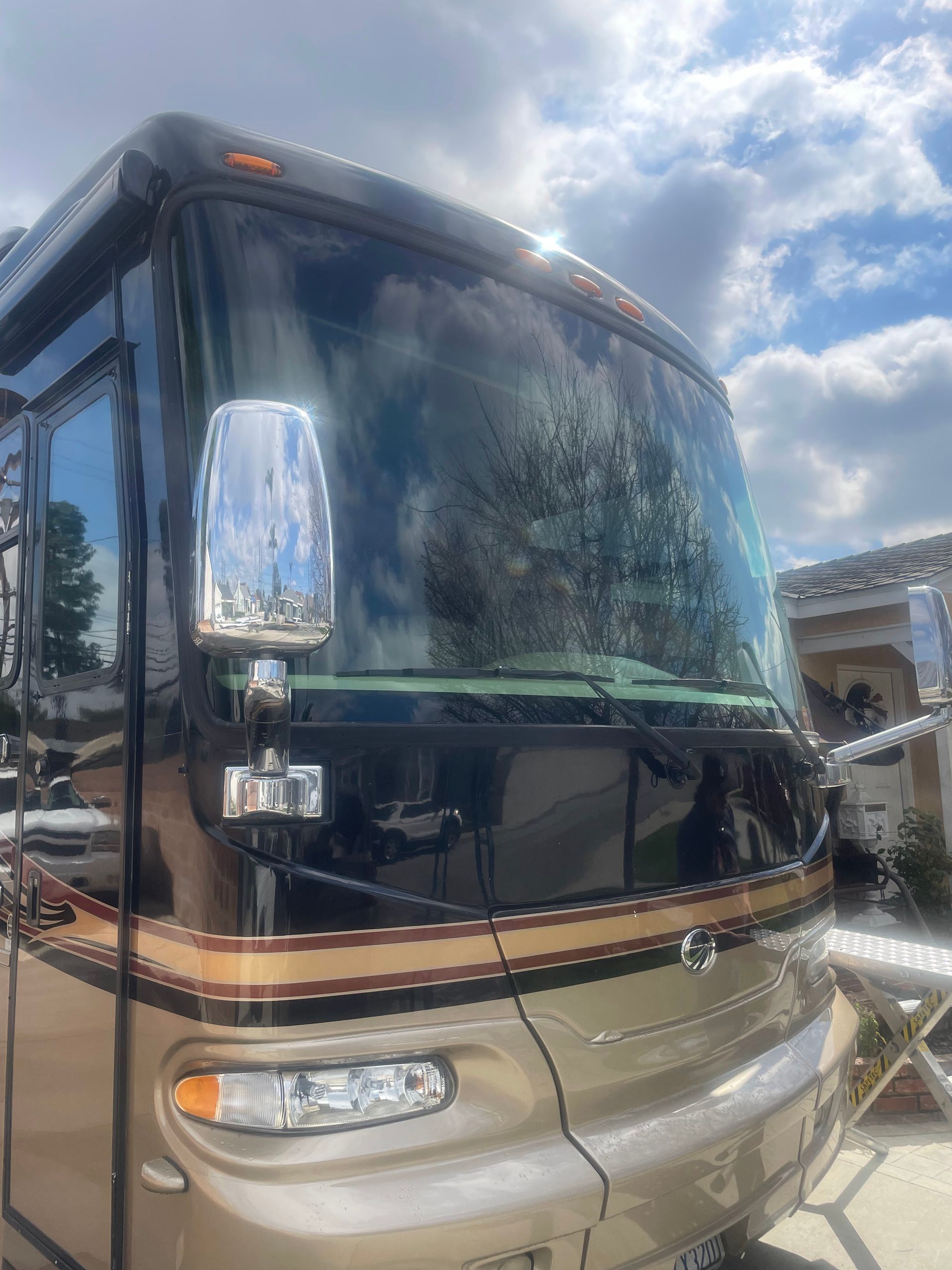 Front view of a tan and black motorhome under a cloudy sky