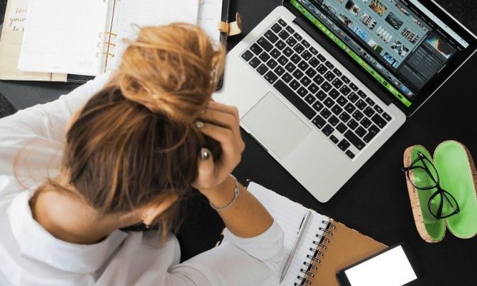 woman at laptop holding head in hands