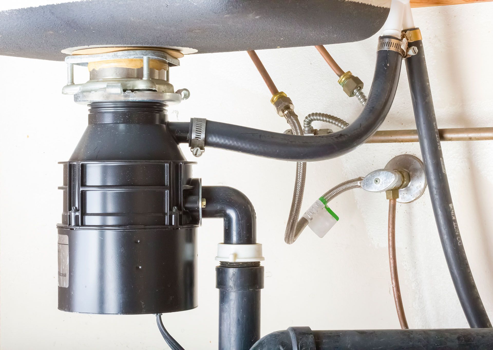 A garbage disposal is under a sink in a kitchen