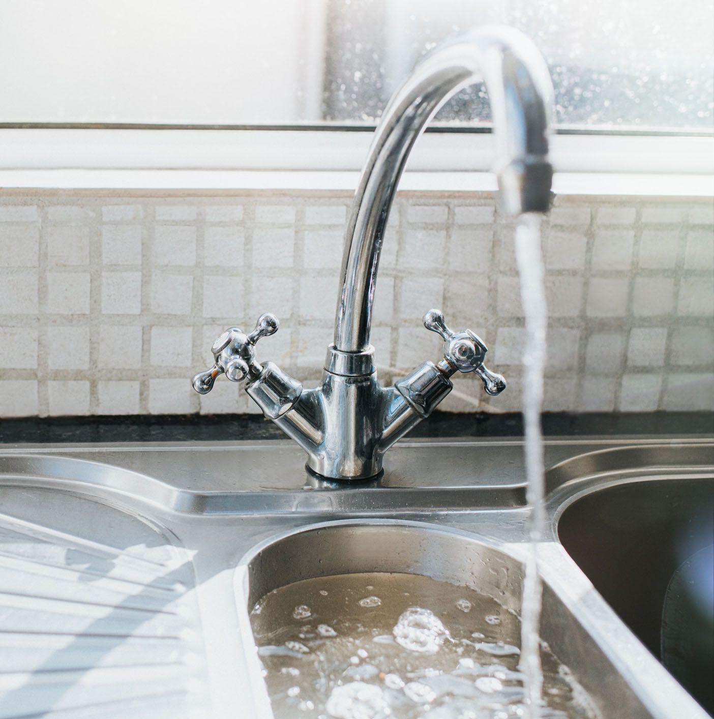 A kitchen sink with water running from the faucet