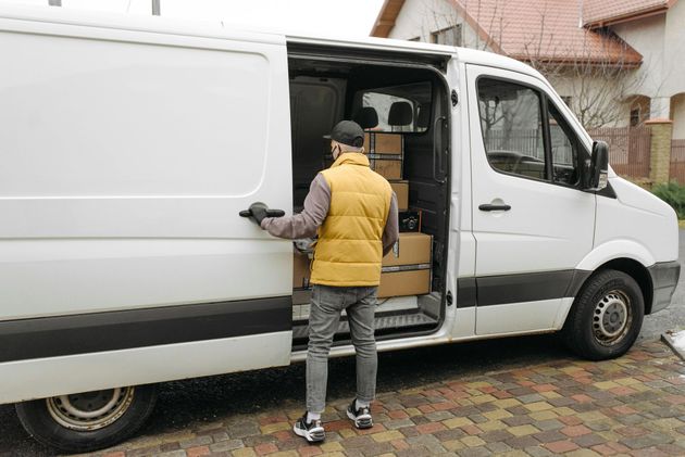Due persone caricano scatole di cartone su un camion, una delle quali utilizza un carrello.