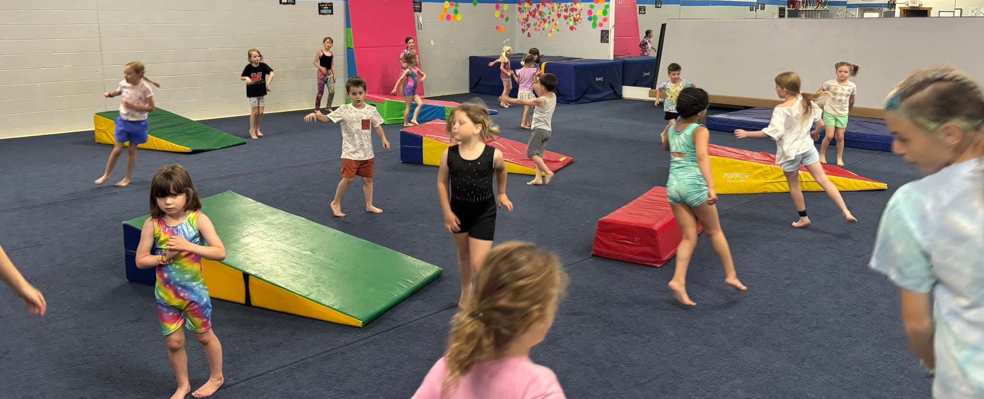 A group of children are sitting on the floor playing with hula hoops.