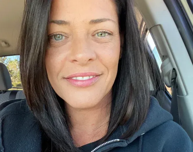 A woman is smiling while sitting in a car.