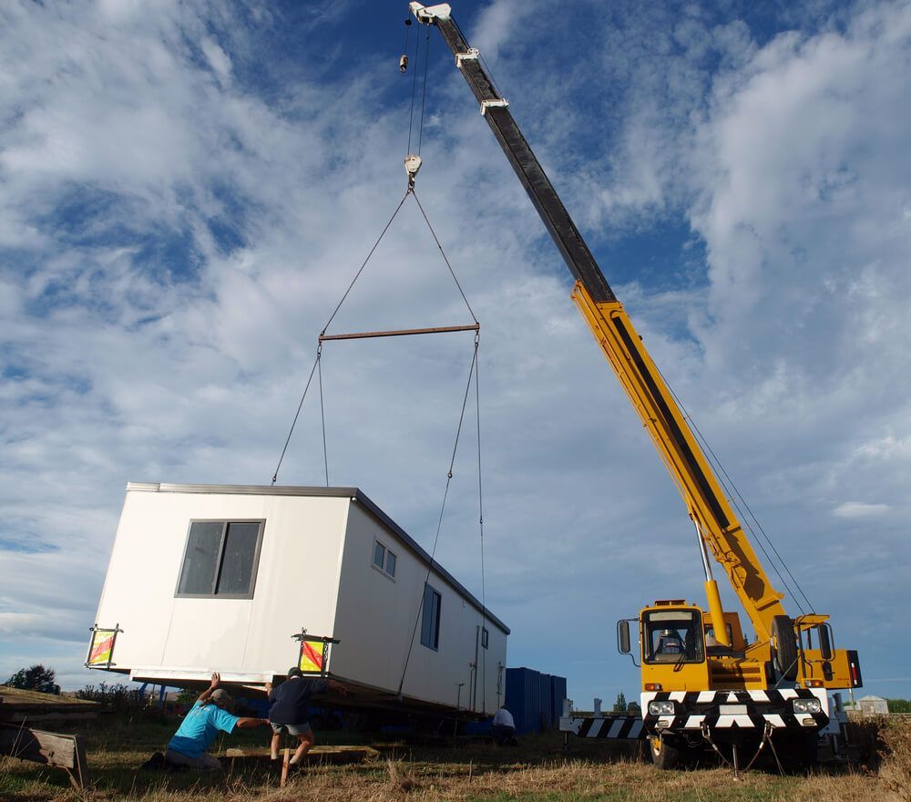 A Yellow Crane Is Lifting A Small White Building — ADR Engineering in Collinsville, QLD