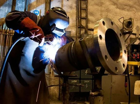 A Man Is Welding A Large Pipe In A Factory — ADR Engineering in Collinsville, QLD