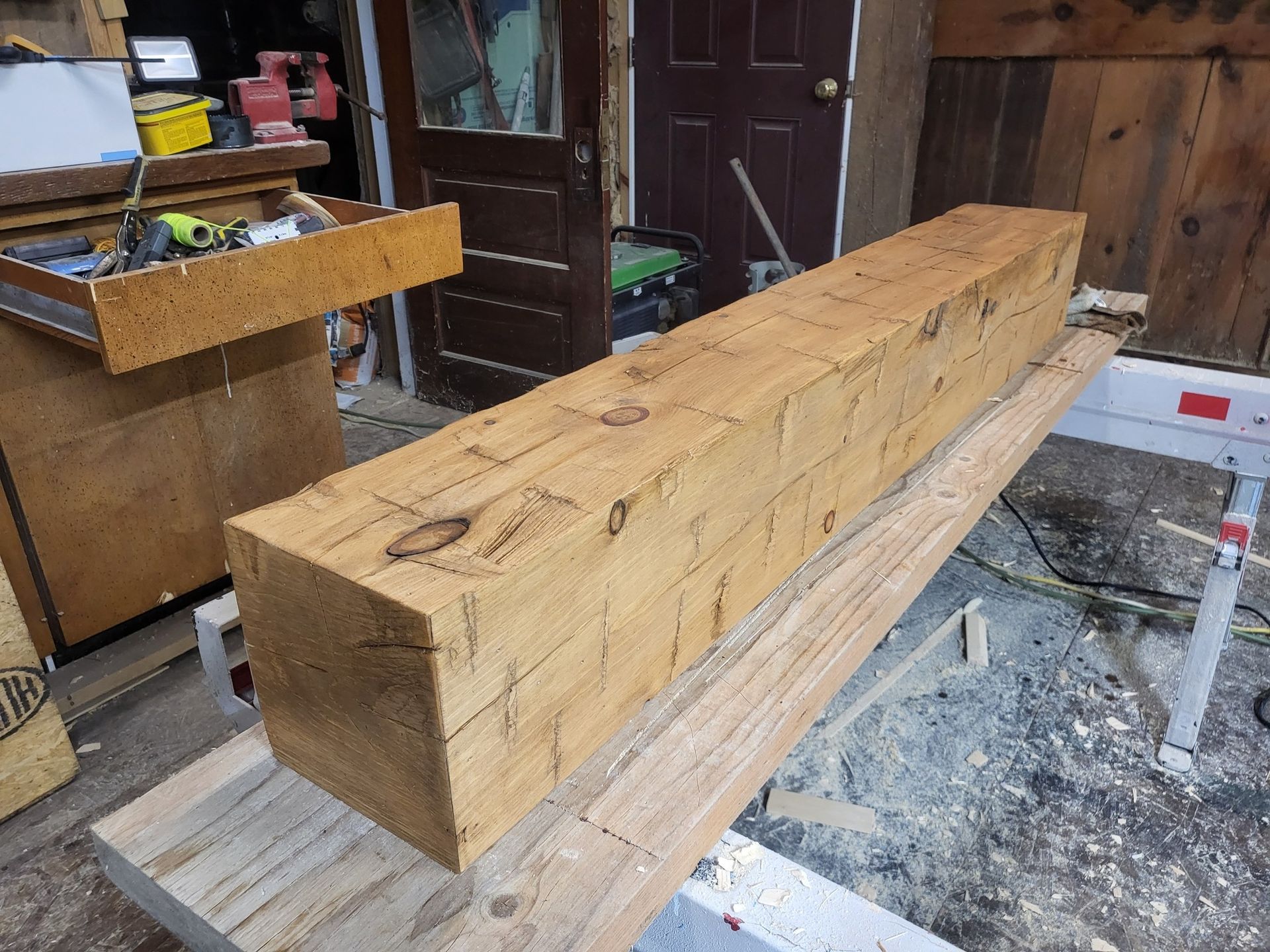 Large rough-cut wooden beam on sawhorses in a workshop/garage