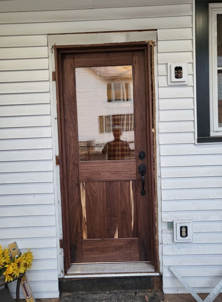 Wooden front door with glass panes on a white-sided house porch