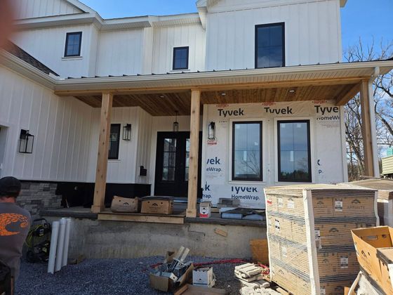 Partially built house with white Tyvek-wrapped exterior and stacked stone materials in front