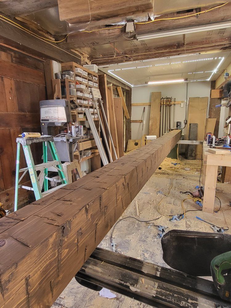 Wood beam being installed in a cluttered workshop under renovation, with ladders and tools nearby