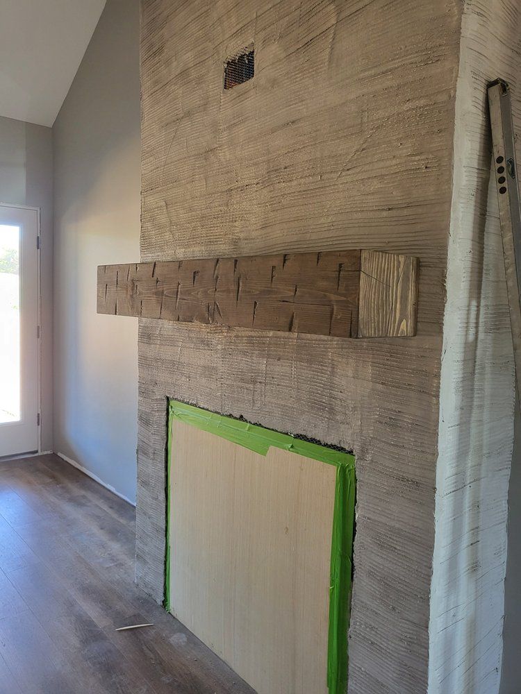 Partially finished fireplace with green painter’s tape in a room with wood flooring