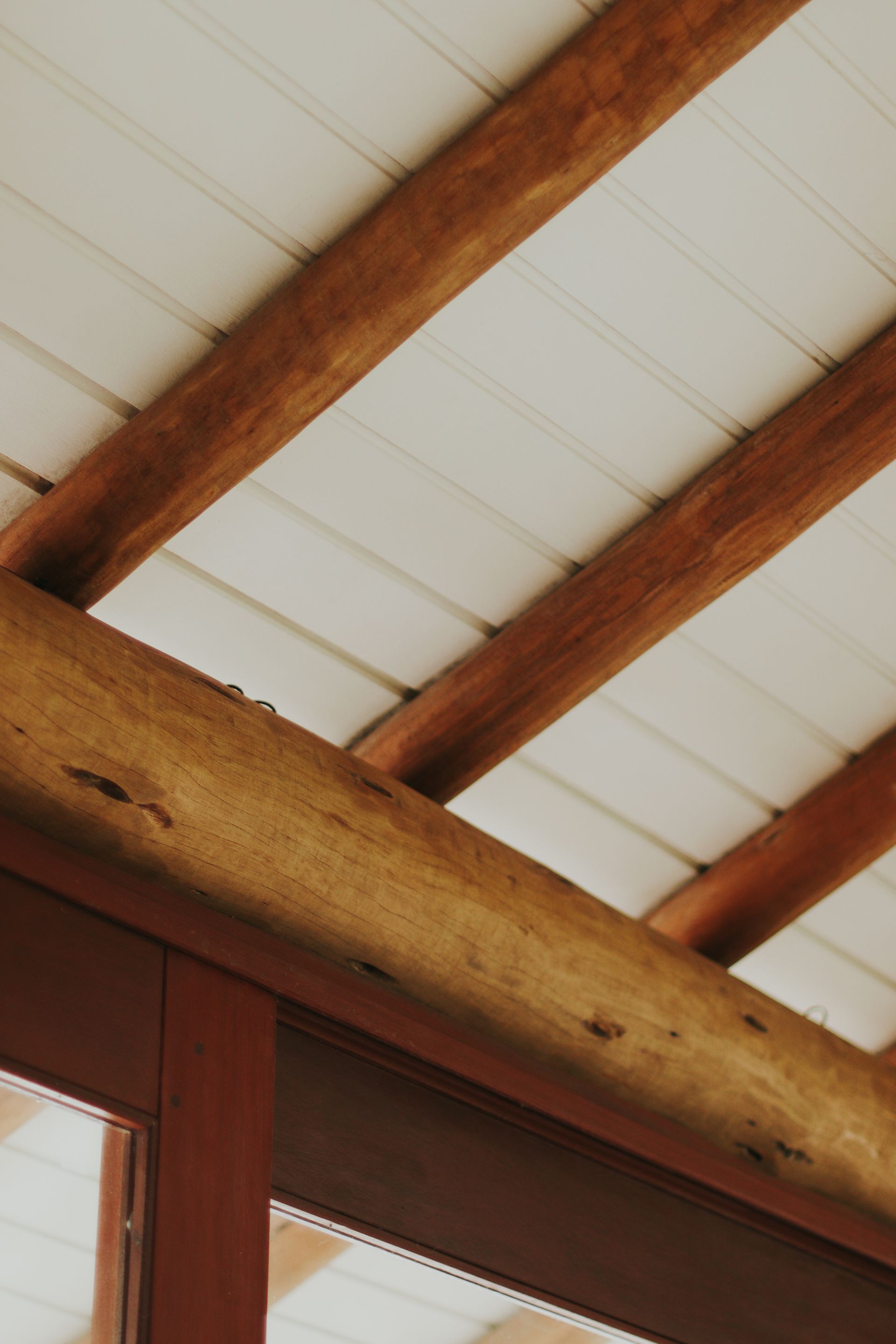 Wooden ceiling beams and white paneling above a doorway with red trim